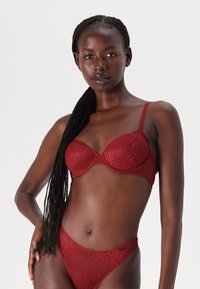Rød blonderbh og matchende bikinitruse med blomstermønster, underwire støtte, tynne justerbare stropper og en jevn tekstur.