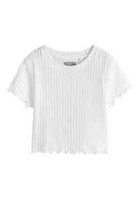 Top court blanc à manches courtes texturé avec encolure ronde, bords froncés et motif ondulé vertical subtil.