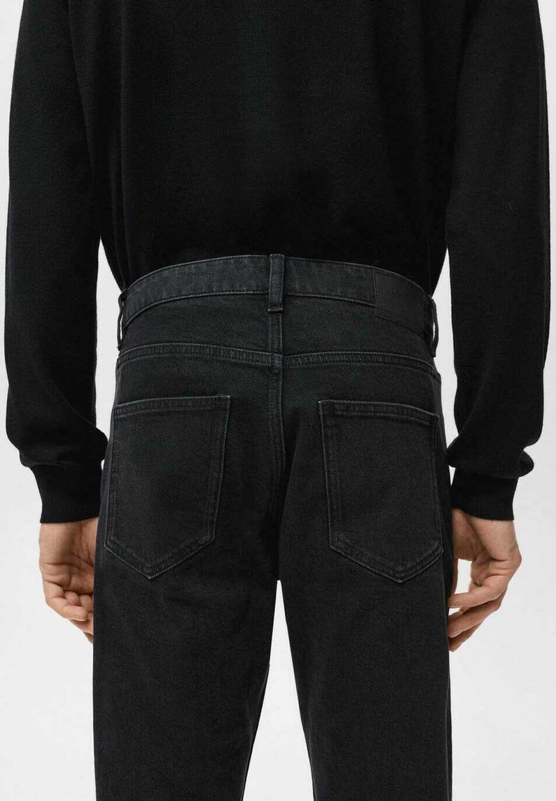 Jean en denim noir à coupe ajustée, avec une coupe droite, deux poches arrière et une ceinture texturée.