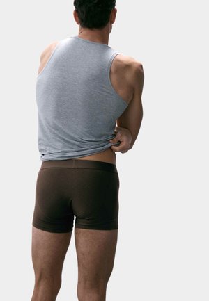 Šedý tílko a hnědé přiléhavé boxerky na muži, se zaměřením na texturu látky, těsný střih a jednoduchost designu.