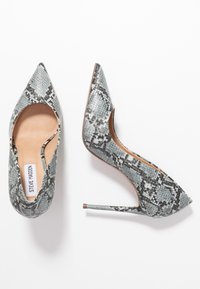 Des escarpins à bout pointu en imprimé serpent texturé gris et noir, avec un talon aiguille et une semelle intérieure lisse couleur tan. Comprend une étiquette de logo à l'intérieur.