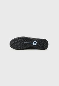 Black athletic shoe sole with textured rubber, featuring a circular pattern and a blue logo accent. Rounded heel for improved traction.