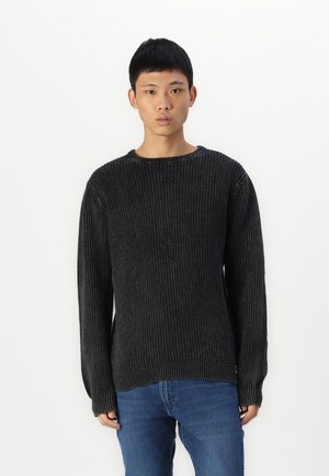 Pull en maille côtelée noire avec un col rond et des manches longues, présentant un motif texturé et un ourlet qui descend à l'arrière.