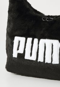 Svart faux fur skulderveske med en dristig hvit "PUMA" logo. Inkluderer glidelås og myk tekstur. Kompakt og buet design.