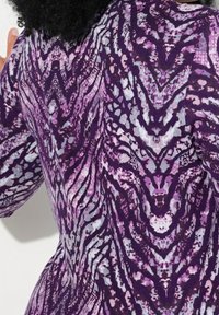 Tissu texturé avec un motif abstrait violet, rose et gris ressemblant à des imprimés animaliers, avec une surface lisse et une forme fluide.