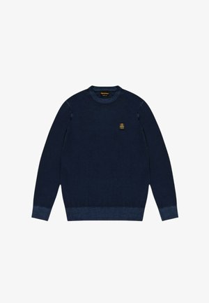 Maglione blu navy con scollo rotondo, maniche lunghe, polsini e orlo a coste, e una piccola toppa con logo sul petto. Tessuto lavorato a maglia dalla texture liscia.