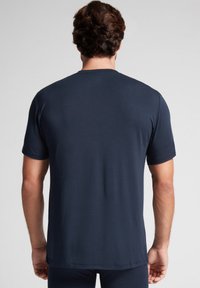 Granatowa koszulka z krótkim rękawem wykonana z miękkiego materiału, z okrągłym dekoltem i luźnym krojem, o gładkiej i równej strukturze.