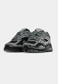 Sportovní boty s černou a šedou síťovinou, texturovanou gumovou podrážkou, reflexními detaily a polstrovaným límcem pro podporu.