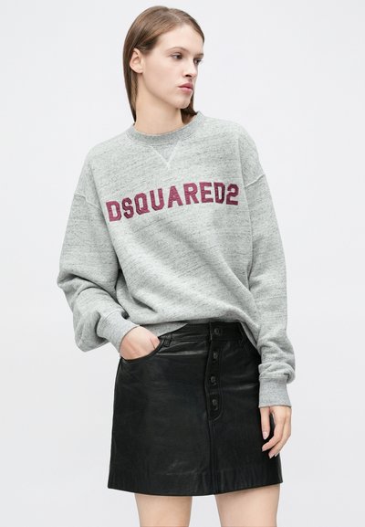 Pelēks džemperis ar "DSQUARED2" logotipu bordozā krāsā, kombinēts ar melnu ādas svārku ar pogām un sānu kabatām.