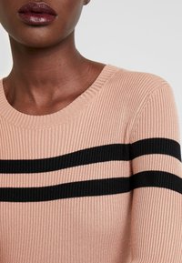 Helles rosa geripptes Sweatshirt mit schwarzen horizontalen Streifen, Rundhalsausschnitt und strukturiertem Stoff. Nahaufnahme des Oberkörpers.