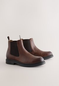 Hnedé kožené Chelsea čižmy s čiernymi elastickými bočnými panelmi, zaoblenými špičkami, pútkami na ťahanie a textúrovanými podrážkami pre lepšiu priľnavosť.