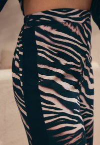 Zebra-print broek in zwart en roze met een gladde textuur, voorzien van een zijpaneelontwerp en een aansluitende tailleband.