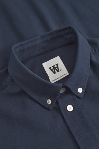 Navy blue button-down shirt with white buttons and a collar label reading "Double Y by Wood Wood."