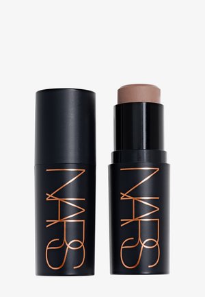 Crayon de maquillage NARS noir avec le capuchon enlevé, montrant un produit crème beige à l'intérieur, posé sur un fond blanc uni.