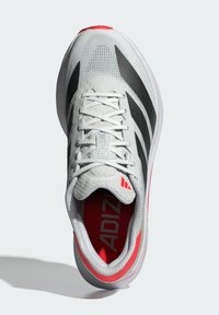 Adidas running shoe featuring a white mesh upper with black stripes, a red accent on the heel, and a padded collar. Lightweight design.