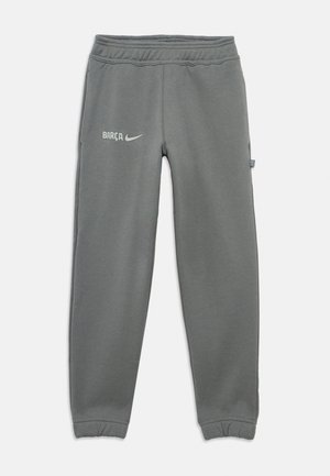 Pantalons de survêtement gris de sport avec taille élastique et poignets, affichant le texte "BARÇA" et le logo Nike sur la cuisse supérieure gauche.