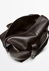 Dunkelbraune Lederreisetasche mit strukturierter Außenseite, ausgestattet mit einer breiten Öffnung, stabilen Griffen und Reißverschluss, die großzügigen Innenraum bietet.