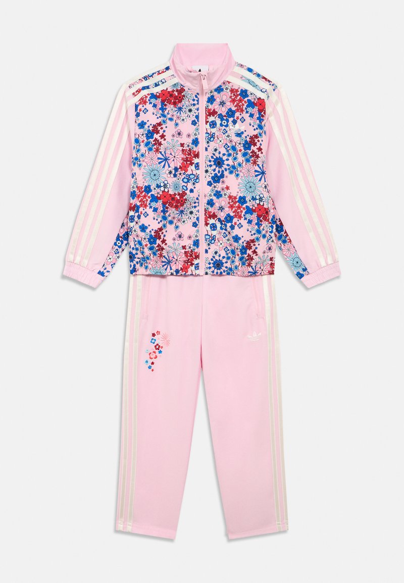 Tuta con stampa floreale rosa con strisce bianche. La giacca presenta un motivo floreale colorato; i pantaloni hanno dettagli floreali e un logo.
