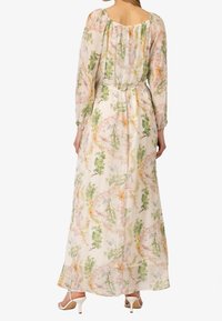 Robe maxi florale en tissu léger. Elle présente des manches cloche, un décolleté dénudé, une taille cintrée et un imprimé floral multicolore dans des teintes douces.