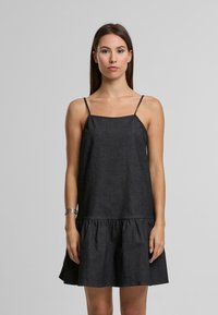 Melna denima kleita ar plānām regulējamām siksnām, taisnu augšdaļu un izplestu, sakopotu svārku. Audumam ir gluda, matēta tekstūra.