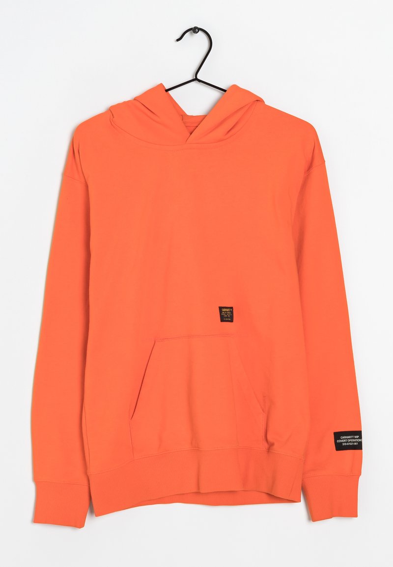 Sweat à capuche orange vif avec poche avant et étiquettes noires sur la poche et la manche gauche, suspendu à un cintre noir sur fond blanc.