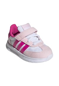 Zapatilla deportiva rosa y blanca con parte superior de ante, lengüeta de malla y tiras de velcro, que presenta tres franjas rosas prominentes en el costado.