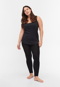 Črna rebrasta majica brez rokavov in črne leggins hlače, ki se prilegajo telesu, z mehkega materiala. Brez vidnih vzorcev, minimalistična zasnova.