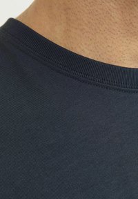 Camiseta de cuello redondo en azul marino con cuello acanalado; textura suave y patrón de tela sutil; vista en primer plano del escote y el área superior del hombro.