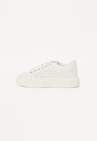 Białe perforowane skórzane sneakersy z płaską białą podeszwą i sześcioma metalowymi oczkami, wyróżniające się wyściełanym kołnierzem i gładką teksturą.