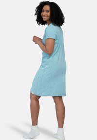 Hellblaues Kurzarmkleid mit lockerer Passform, das ein gepunktetes Muster aufweist und ein Etikett auf der linken Seite trägt, kombiniert mit weißen, flauschigen Socken.