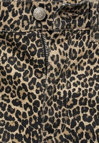 Primo piano di un tessuto con stampa leopardata che presenta una tasca con zip, una trama testurizzata e colori a contrasto di nero e beige con un accento in metallo.