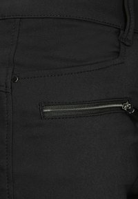 Svarta byxor med en dragkedja, gjorda av slät tyg med subtila sömnadsdetaljer. Designen inkluderar en figursydd siluett.