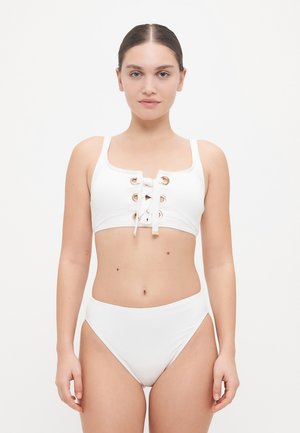 Witte bikini set met een cropped top voorzien van gouden gaten en een vetersluiting, gecombineerd met hoge taille onderkanten. Soepele textuur.