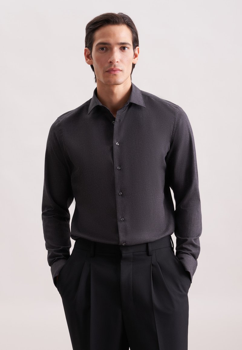 Camicia button-up grigia scura con una texture sottile, maniche lunghe e colletto strutturato, abbinata a pantaloni neri su misura.