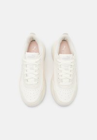White sneakers with a smooth leather upper, perforated toe, tonal laces, and pastel accents on the sides, featuring a textured sole.