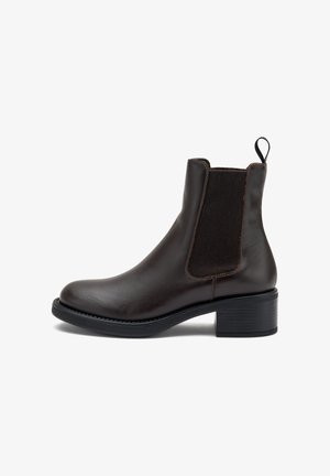 Bota de cuero marrón hasta el tobillo con paneles laterales elásticos, puntera redondeada, tacón negro texturizado y lengüeta para facilitar el calzado. Diseño limpio y construcción robusta.