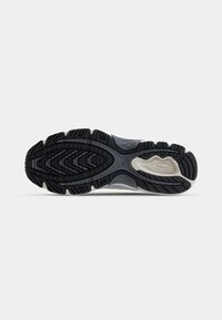 Semelle extérieure en caoutchouc noir avec un motif de traction texturé ; présente une semelle intermédiaire grise avec des accents clairs et un design lisse et courbé.