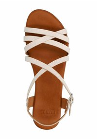 Tan leather sandal with cross straps in cream, featuring a flat sole, adjustable ankle strap, and textured footbed.