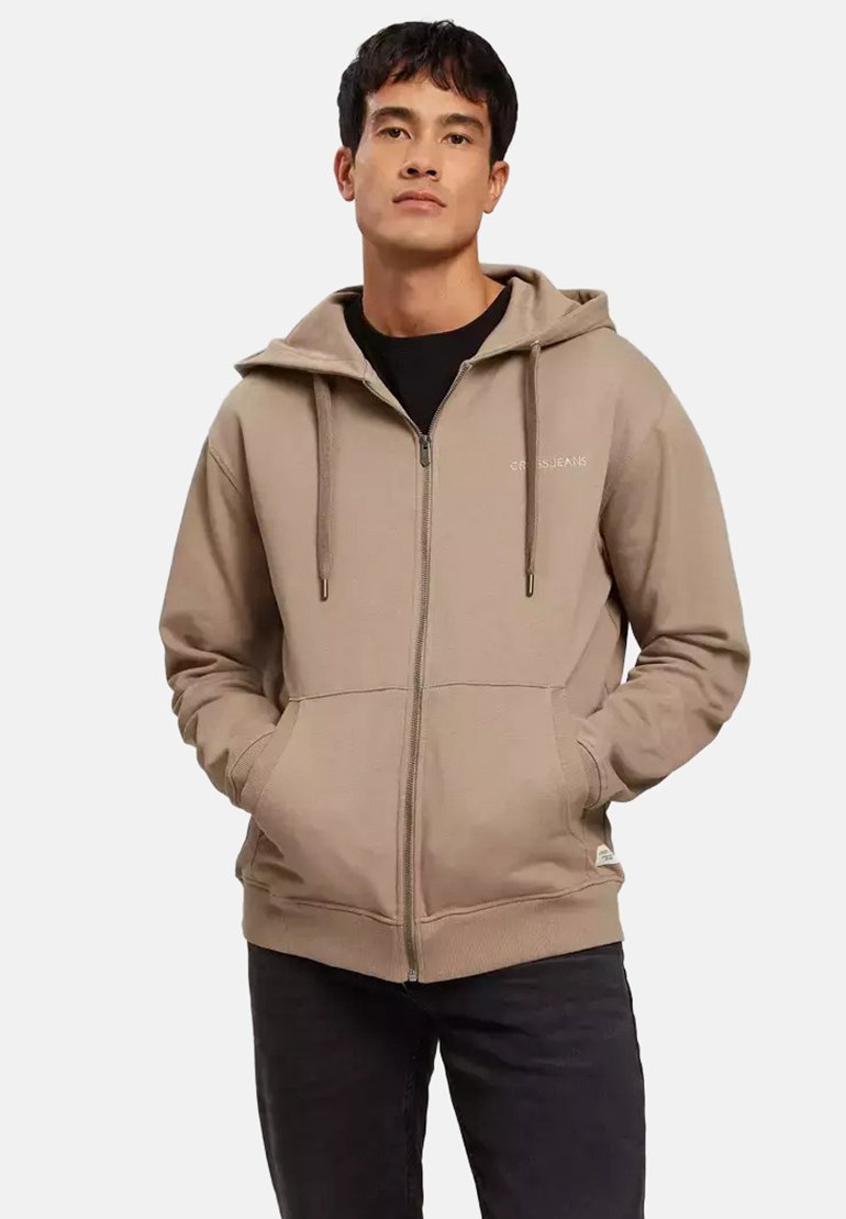 Beżowa bluza z zamkiem, wykonana z miękkiego materiału, z kapturem na sznurku, dwoma przednimi kieszeniami i haftowanym logo na lewej piersi.