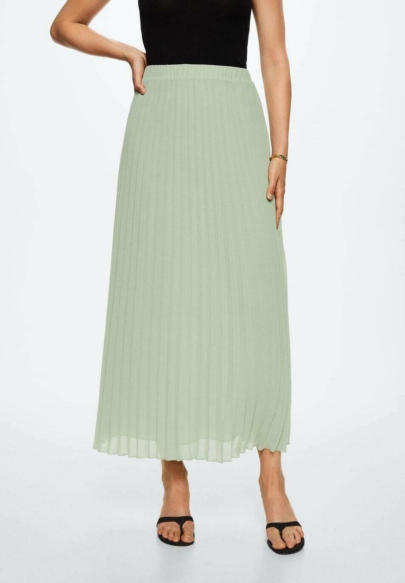 Falda maxi plisada de color verde claro con cinturilla elástica. Presenta un diseño fluido y se combina con sandalias planas negras.