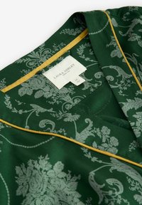 Tessuto verde a motivo floreale delicato, accentuato da un bordo giallo al colletto. Etichetta con la scritta "Laura Ashley", taglia M.