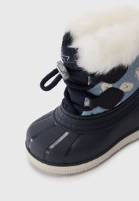 Botas de invierno azul marino con forro de felpa blanca, parte superior de tela estampada, cordones de bloqueo seguros y suela de goma texturizada.