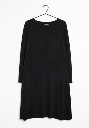 Robe noire à manches longues, longueur genou, avec un col rond, suspendue à un simple cintre noir sur fond blanc.