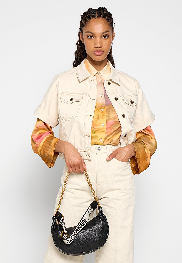 Chaqueta de mezclilla beige, blusa con degradado en naranja y amarillo, pantalones crema y bolso de cuero negro con cadena dorada y correa con estampado.
