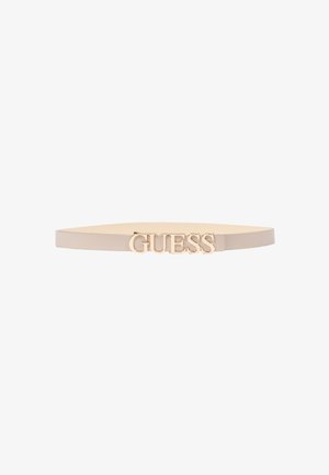 Cintura sottile beige con fibbia centrale in metallo dorato con logo "GUESS" su sfondo bianco.