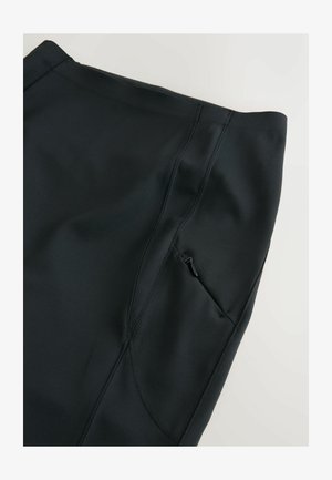 Black activewear leggings with a smooth, stretchy texture, featuring a side pocket with a zipper and visible seam details.