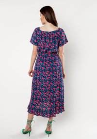 Blauwe bloemen maxi-jurk met korte mouwen, geplooide halslijn en een cinched taille. Voorzien van roze bloemen en een gerimpelde zoom. Groene enkelbandjes.