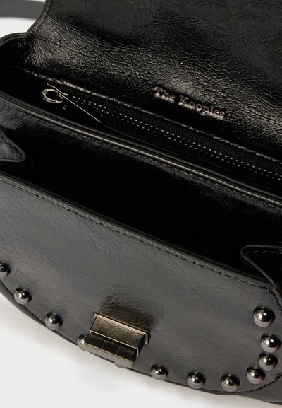 Μαύρη δερμάτινη τσάντα με ασημένια καρφιά, μεταλλικό κούμπωμα και ανοιχτή θήκη με φερμουάρ που δείχνει το λογότυπο "The Kooples" στο εσωτερικό.