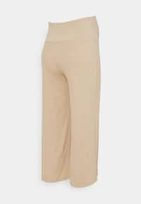 Béžové ribbed kalhoty s širokým elastickým pasem. Materiál je měkký s vertikální strukturou. Zkrácená délka s bočními rozparky na lemu.