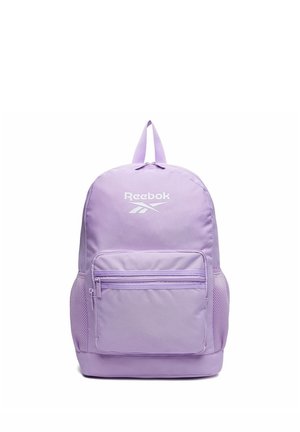 Lilla Reebok rygsæk med lynlåslomme foran, netlommer i siderne og topgreb mod en hvid baggrund.